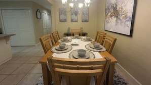 A dining room with a round table, six wooden chairs, and a chandelier. - Stylish 4-bedroom, 3 Bath Townhome in Valdosta (Valdosta)
