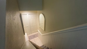 A staircase with a handrail, a landing with a door, and a wall-mounted mirror. - Stylish 4-bedroom, 3 Bath Townhome in Valdosta (Valdosta)