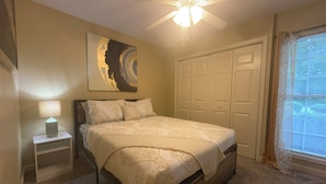 A bedroom with a bed, nightstand, ceiling fan, and closet. - Stylish 4-bedroom, 3 Bath Townhome in Valdosta (Valdosta)