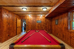 A pool hall with a red pool table, wooden walls, and a sign indicating it's a public space. - Black Eagle Lodge -  Unique - 8 Bedrooms - 2 Pools (Logan)