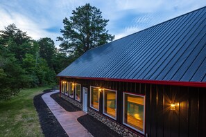 A building with a metal roof, a stone foundation, and a pathway leading to the entrance. - Black Eagle Lodge -  Unique - 8 Bedrooms - 2 Pools (Logan)