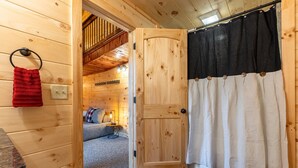 A wooden interior with a door leading to a bedroom, a red towel hanging on a ring, and a black and white curtain. - Black Eagle Lodge -  Unique - 8 Bedrooms - 2 Pools (Logan)