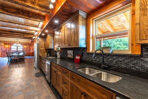Une cuisine spacieuse avec des meubles en bois, un plan de travail noir et une grande fenêtre.