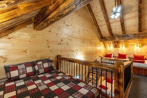 Ein gemütliches Blockhaus-Schlafzimmer mit einem großen Bett, einer Holzbalkendecke und einer kleinen Schreibenecke.