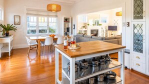 A spacious kitchen with a dining area, wooden flooring, and a built-in pot rack.