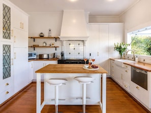 Een moderne keuken met witte kasten, een centraal eiland met krukken, een magnetron, broodrooster en een spoelbak met uitzicht.