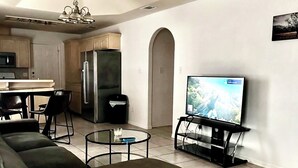 Un salon moderne avec un canapé d’angle, une table basse et un téléviseur posé sur un meuble.