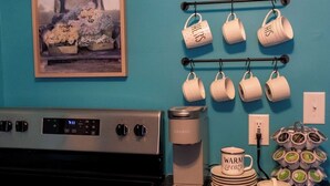 Eine Küche mit einer Kaffeestation, einem Wasserkocher und einem Kaffeetassenhalter.