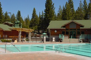 A swimming pool with a wooden deck and a covered area, surrounded by a building with a green roof and a sign that reads "Lodge". - The Viking Haus - Stylish Cabin, Redecorated with Stunning Views, and Close to Hiking Trails (Truckee)