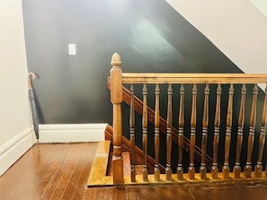 Staircase features a handrail and balusters in a spacious room with a wooden floor.