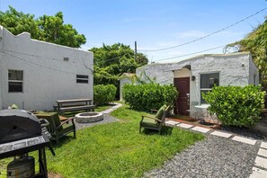 Enjoy al fresco dining and relaxation in the beautifully landscaped yard with a barbecue grill, bench, and seating area.