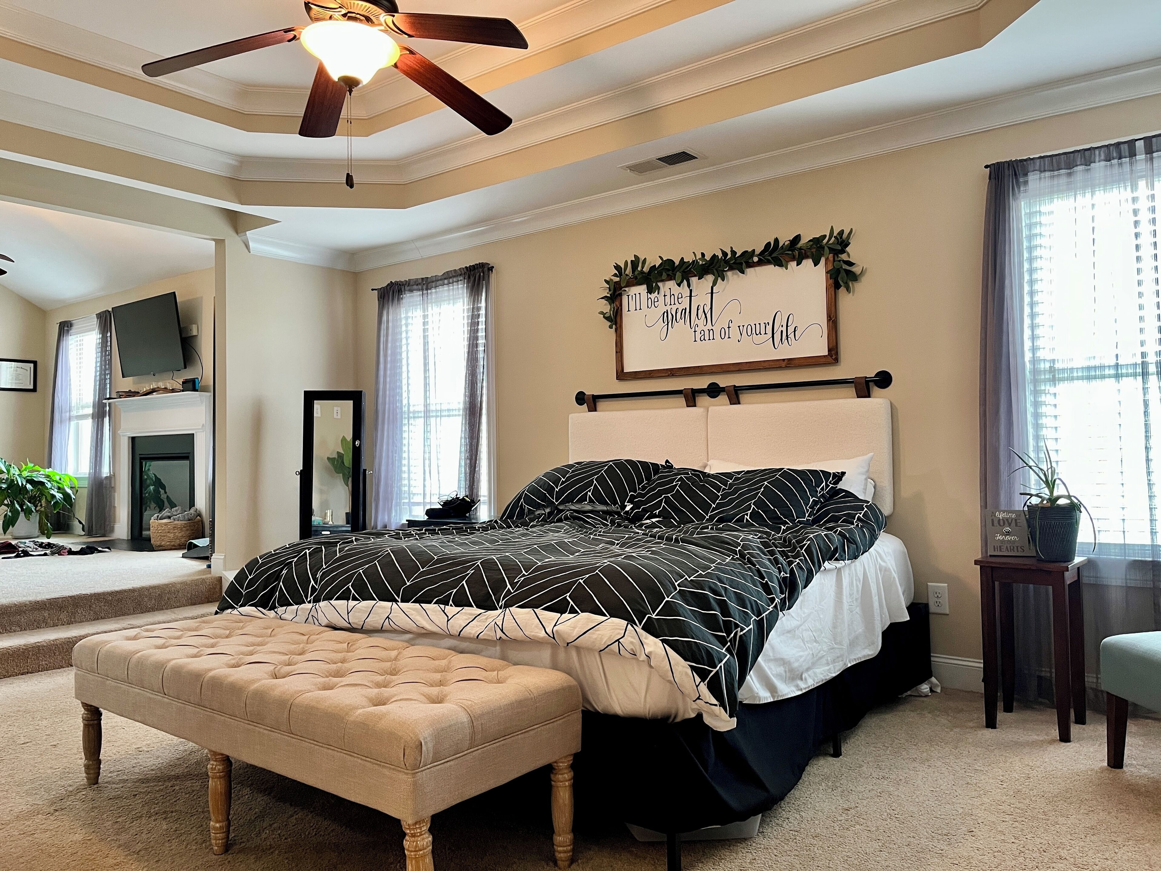 A bedroom with a bed, a ceiling fan, a fireplace, and a sign on the wall.