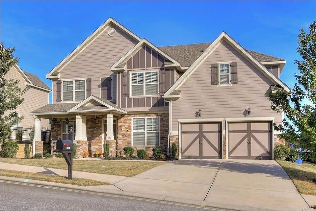 A two-story house with a garage, a front porch, and a mailbox.