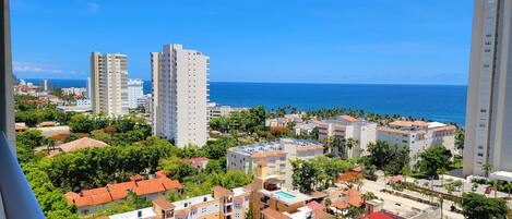 Zona residencial costera con varios edificios altos, cielo azul despejado y vista al océano.