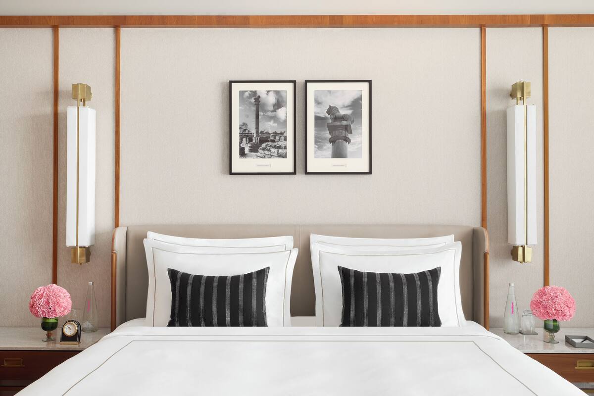 Een hotelkamer met een groot bed, twee nachtkastjes, een wandlamp en twee ingelijste foto's.