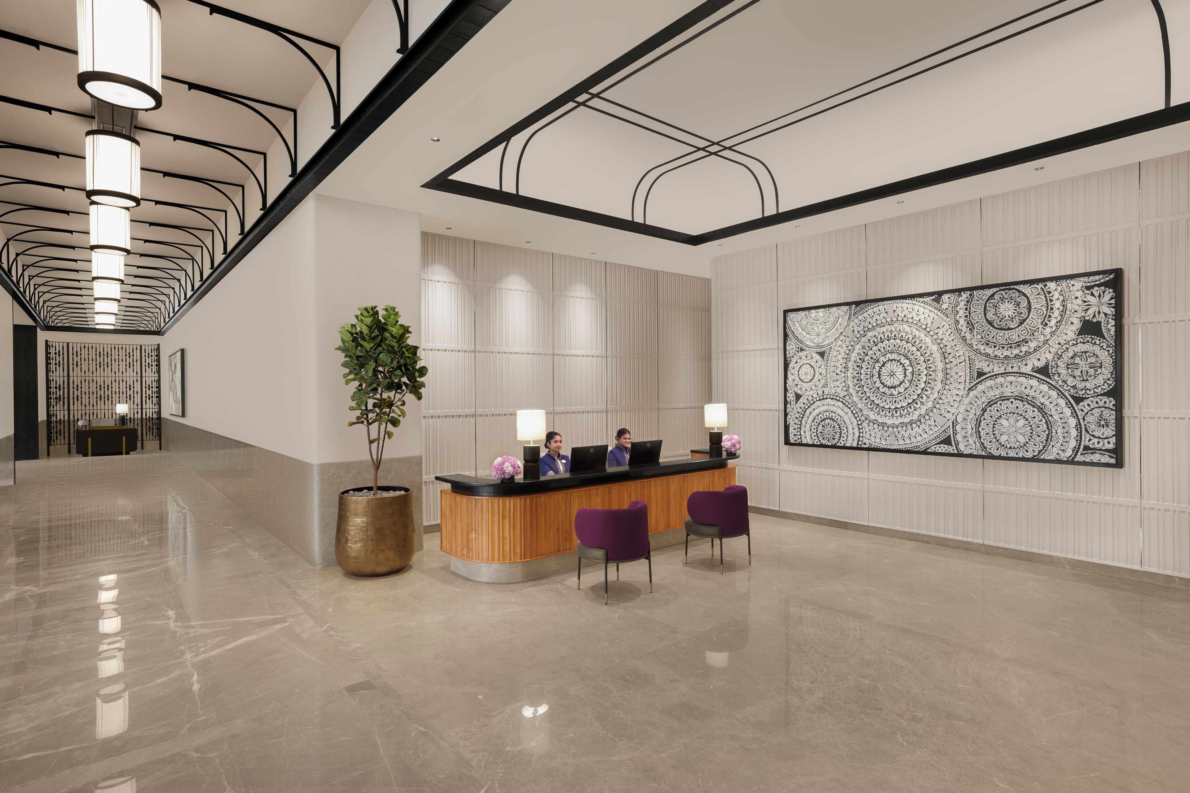 A modern reception area with a wooden reception desk, two purple chairs, a large abstract wall art, and a tall plant.