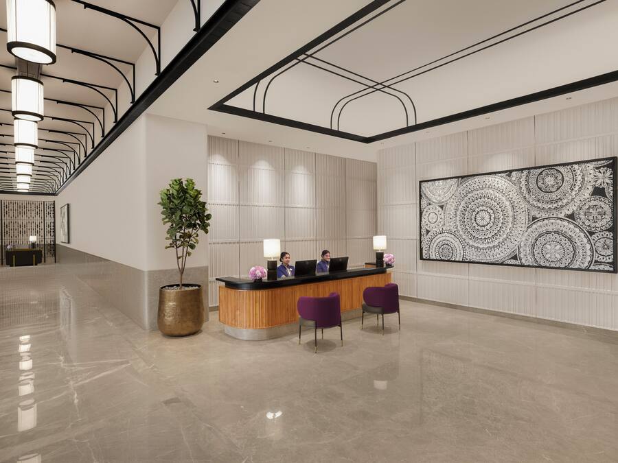 A modern reception area with a wooden reception desk, two purple chairs, a large abstract wall art, and a tall plant.