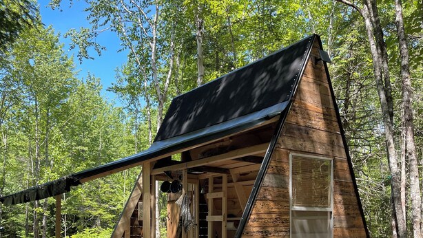 Eine Holzhütte mit geneigtem Dach und einer Veranda.