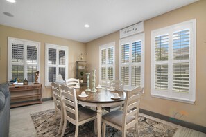 A dining area with a round table, white chairs, and a 'Family' sign on the wall. - The Charming Chateau - Luxe - Resort - Location (Davenport)