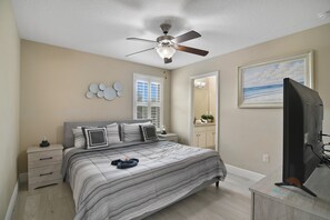 A bedroom with a bed, a ceiling fan, a TV, a dresser, a nightstand, a mirror, and a window. - The Charming Chateau - Luxe - Resort - Location (Davenport)