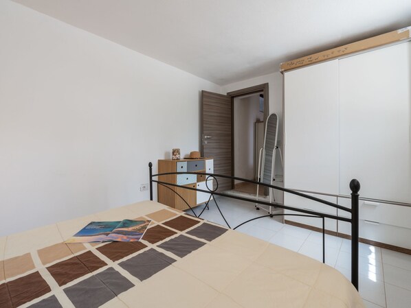 A bedroom with a bed, a dresser, a mirror, and a door leading to a bathroom. - Pintada by Interhome (Villasimius)