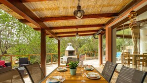An outdoor dining area with a bamboo ceiling, a grill, and a view of the surrounding trees. - Pintada by Interhome (Villasimius)