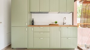 A modern kitchen with light green cabinets, a wooden countertop, and a small plant on the sink area. - Pintada by Interhome (Villasimius)