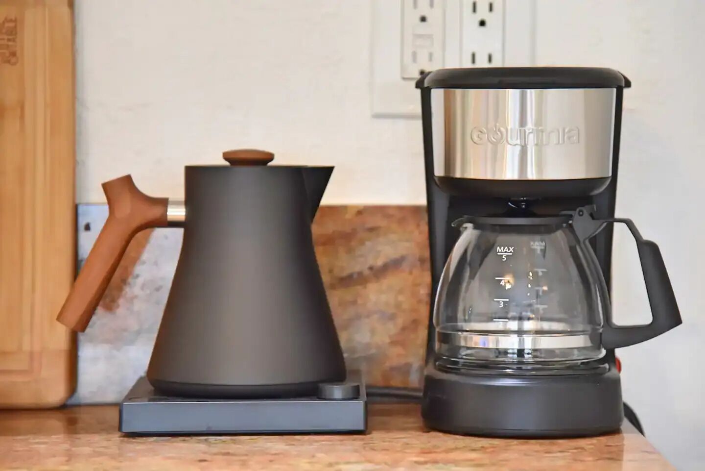 Et moderne køkken med kaffemaskine og elkedel på en bordplade.