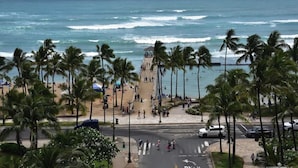 A beach with palm trees, a tower, and the ocean.