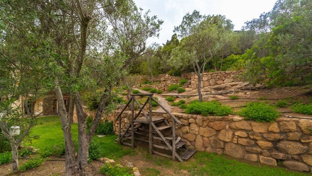 A stone retaining wall with a wooden staircase leading up to a platform.