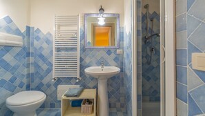 A bathroom with a toilet, sink, and shower.