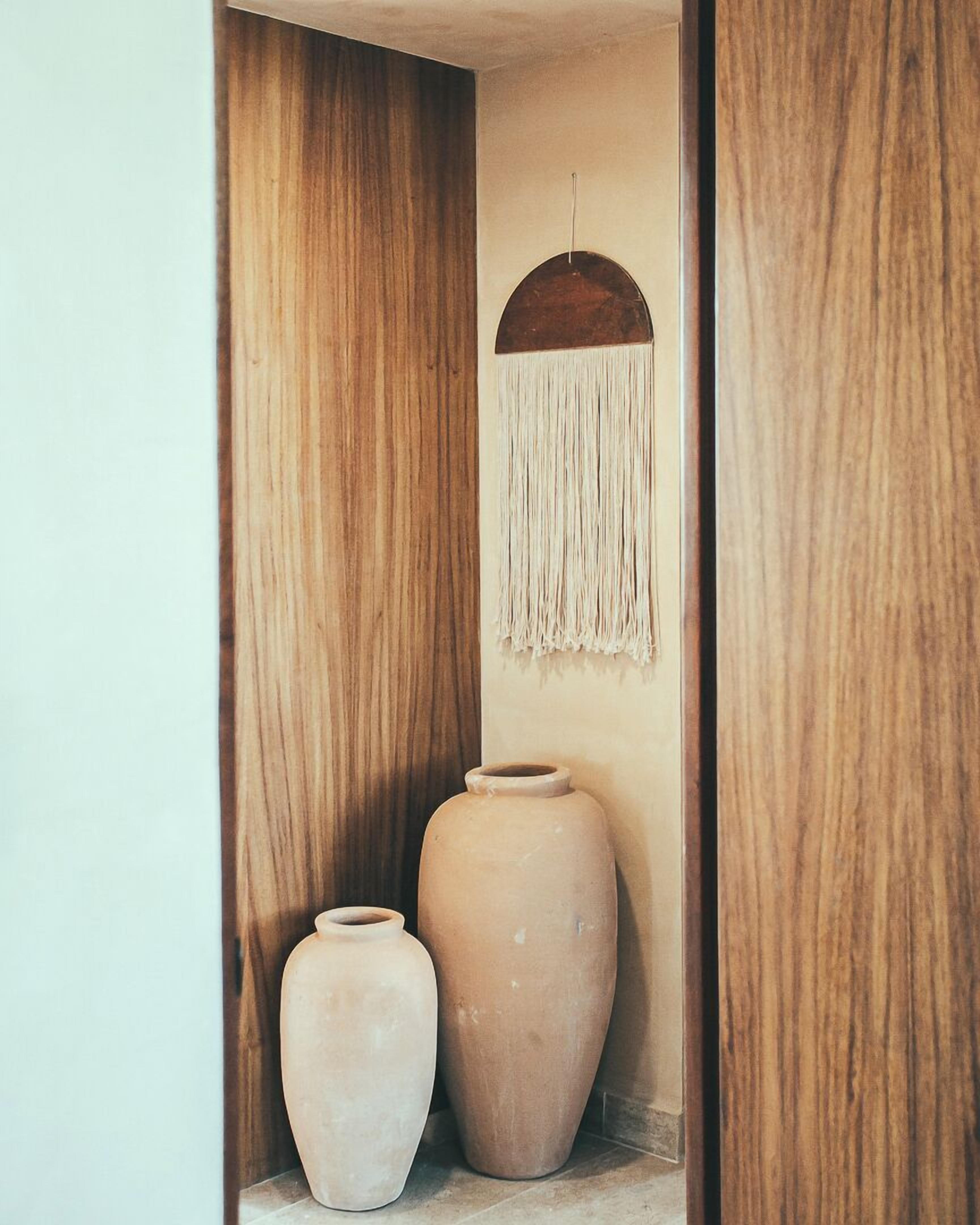 A wooden cabinet with two pottery vases inside.