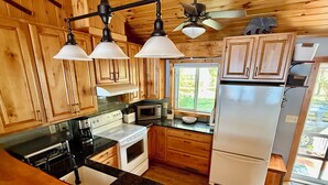 A kitchen with wooden cabinets, a stove, a microwave, and a refrigerator.