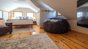 Un dormitorio amplio con una cama grande, un sillón de peluche y vistas al exterior a través de una ventana.