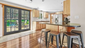 A modern kitchen with a central island, wooden cabinets, and a sliding glass door leading to a patio.