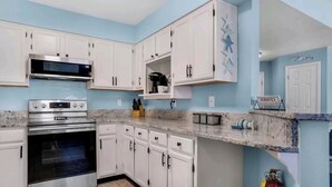 A kitchen with white cabinets, a stainless steel oven, and a microwave. - Seashell Suite! (Destin)