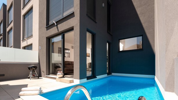 Een modern gebouw met een zwembad, een barbecueplaats en een glazen entree.