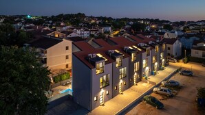 Een modern appartementencomplex met meerdere eenheden, een zwembad en een parkeerplaats.