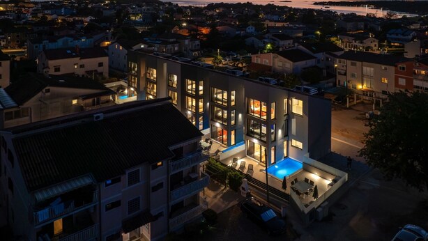 A modern multi-story building with a rooftop pool and outdoor seating area.