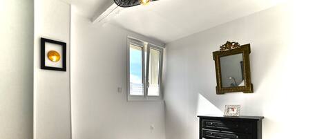 Une chambre à coucher avec un lit, une commode, un miroir, un cadre photo et une fenêtre.