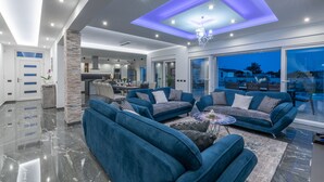 A modern living room with blue sofas, a chandelier, and a view of the outside. - Villa Mersi (Istria - Pula) (Pula)