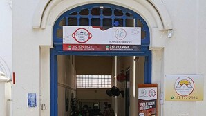 Una entrada a un edificio con un letrero que anuncia 'Cazuelas TORRE JAIME' y 'HOSPEDAJE GIRARDOTA' con números de contacto.