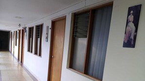 Un largo pasillo con puertas a un lado y ventanas al otro.