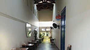 Un pasillo con mesas y sillas, una puerta azul y un cartel en la pared.