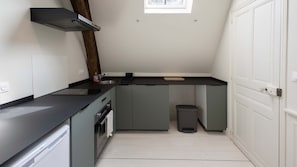 A compact kitchen with a black countertop, a built-in oven, a sink, and a trash bin. - Arras quartier préfecture : 2 pièces calme (Arras)