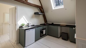 A compact kitchen with a dishwasher, oven, and a small window.
