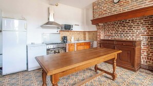 Een keuken met een houten tafel, witte apparaten en een bakstenen muur.