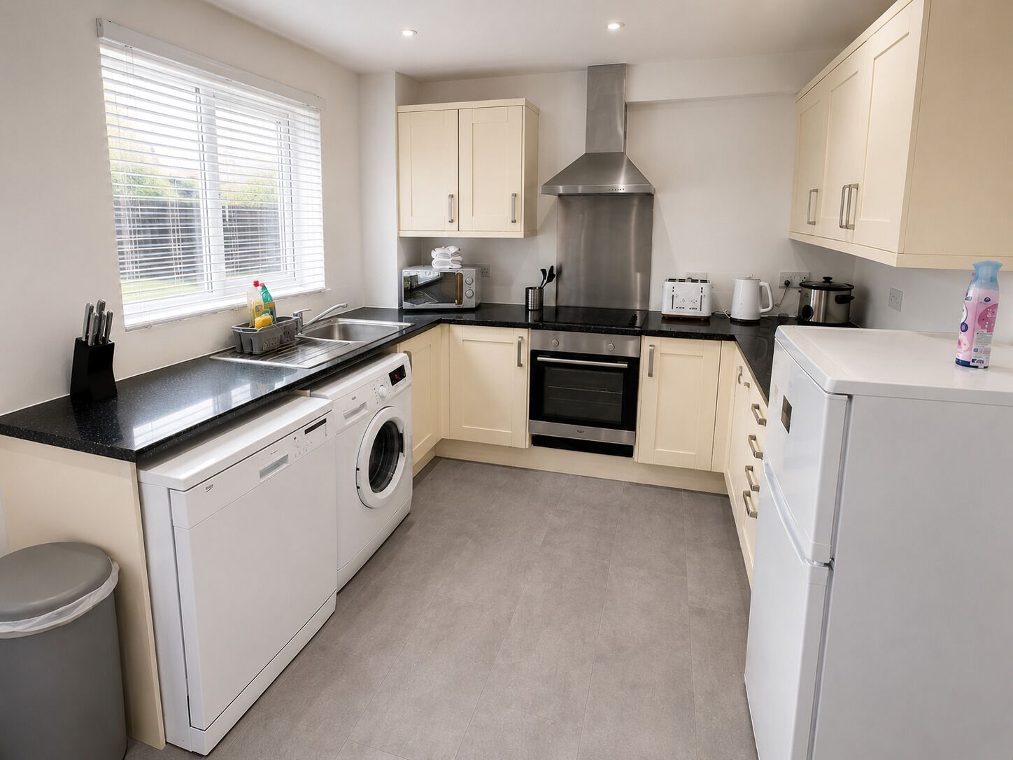 A modern kitchen with a washing machine, oven, and microwave.