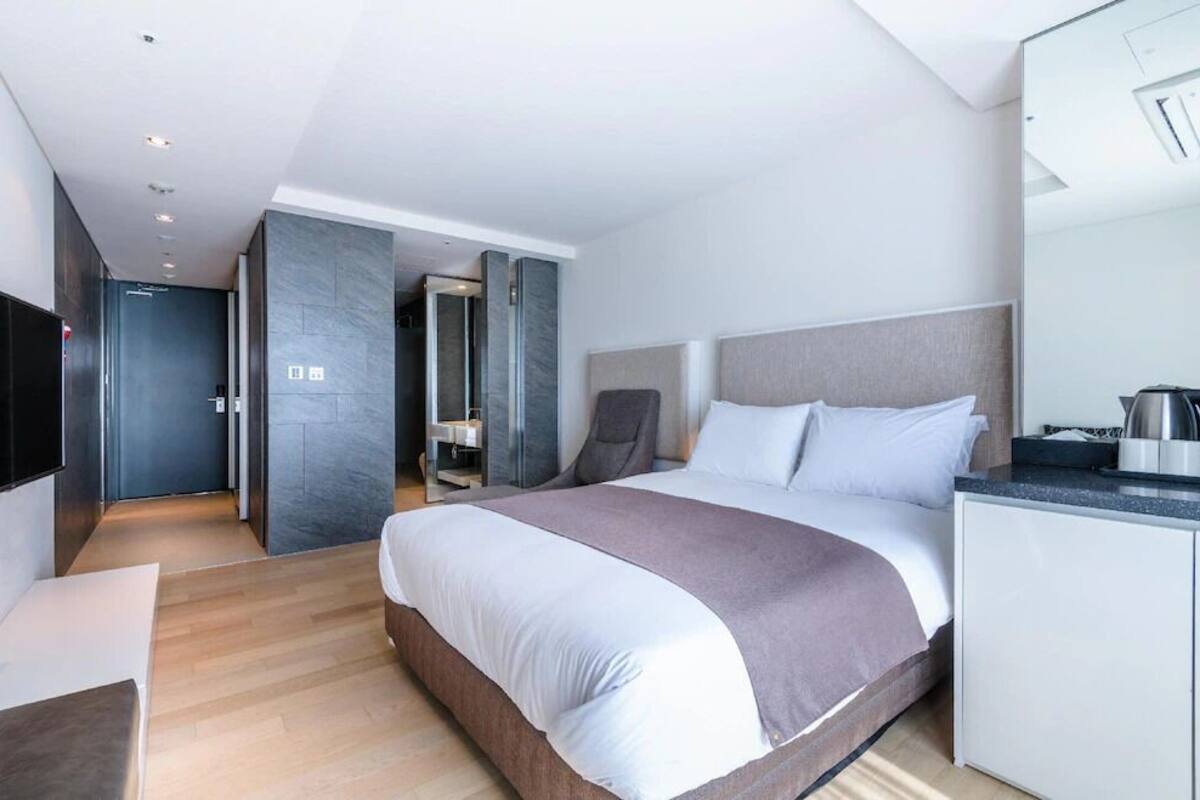 Ein modernes Hotelzimmer mit einem großen Bett, einem Schreibtisch und einer Küchenzeile.