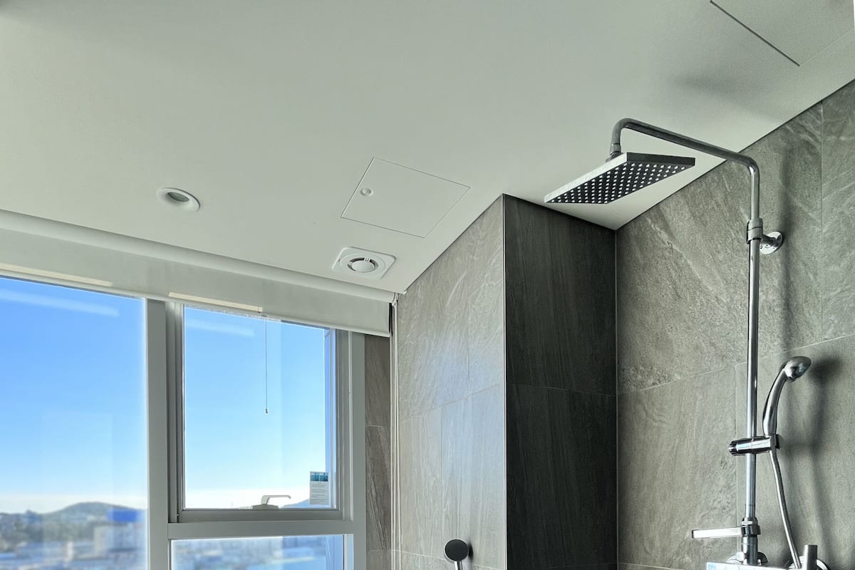 Ein modernes Badezimmer mit einer freistehenden Badewanne, einer Duschbrause und einem Fenster mit Blick auf die Stadt.